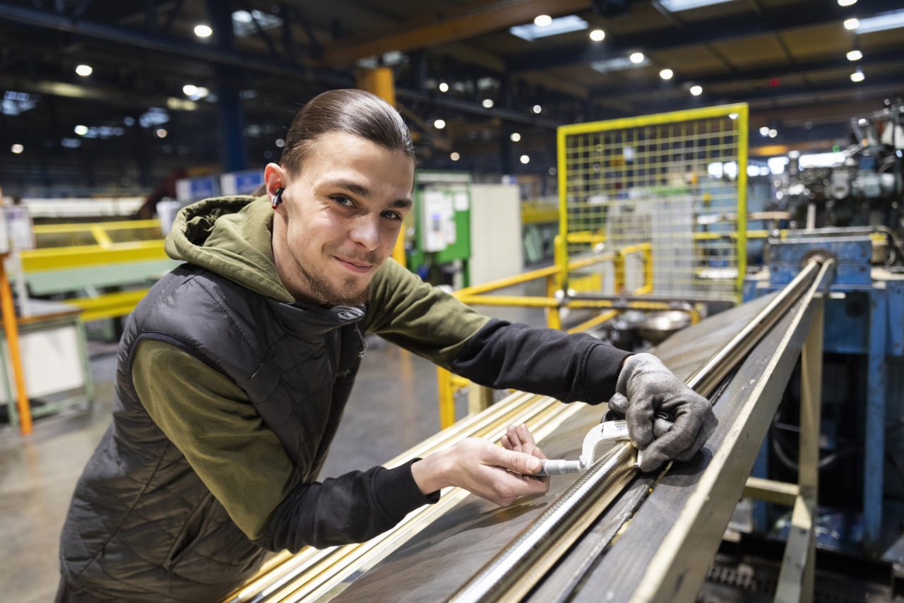 Jeune apprenti souriant au travail dans l'industrie